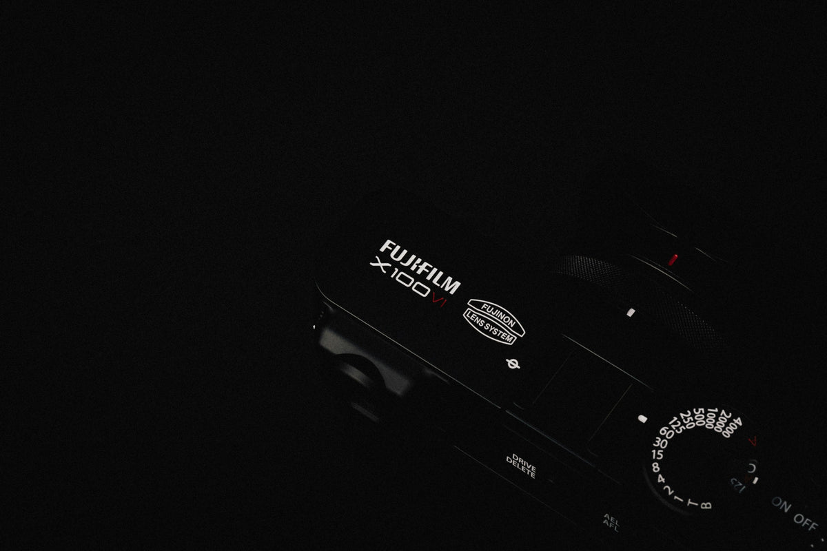 Black Compact Camera — photograph 3. Photo: Howard Bouchevereau; https://unsplash.com/photos/a-close-up-of-a-camera-in-the-dark-P-0MFhdiJxU. Photographic demo.