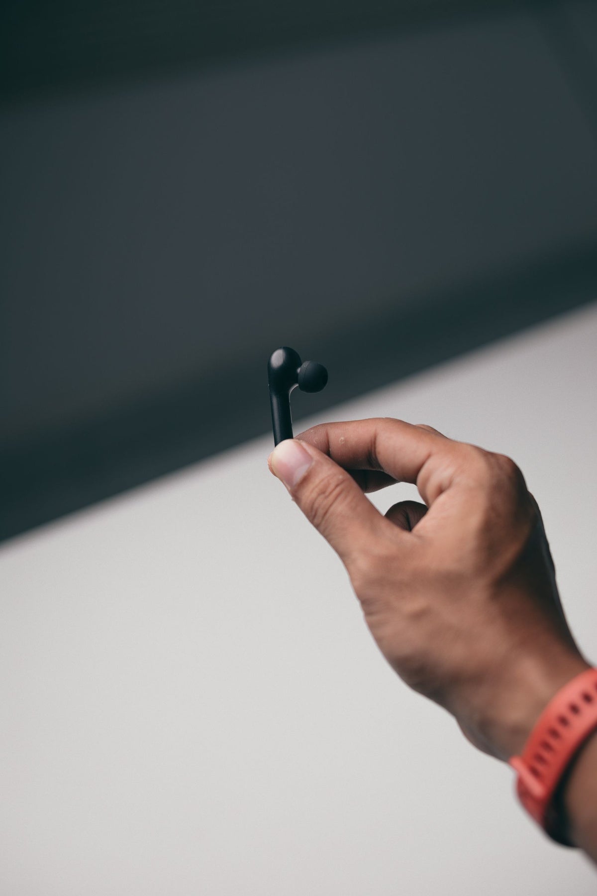 A single wireless earbud held in a hand