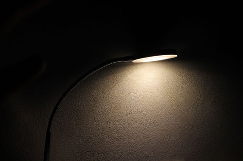 Detail of a desk lamp head casting warm light across a dark desk