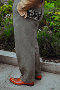 Man wearing grey wool trousers with a camera on a city pavement
