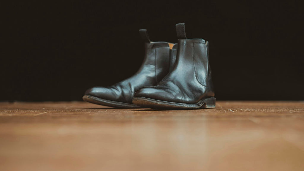 City Chelsea in Black — pair of black polished leather chelsea boots on a wooden surface