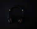 Black over-ear wireless headphones on a dark studio surface
