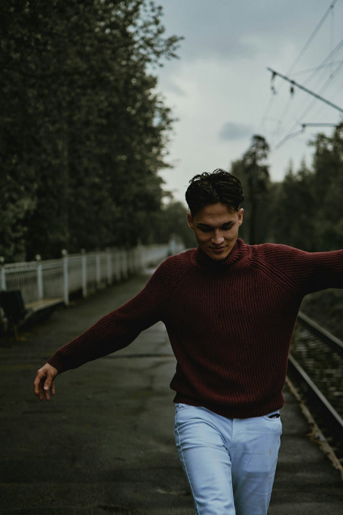 Man wearing a bordeaux crew-neck knit sweater outdoors in natural light