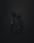 Wireless earbuds beside their open charging case on a dark surface
