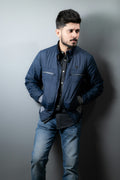 Man wearing a quilted field jacket, standing against a plain wall
