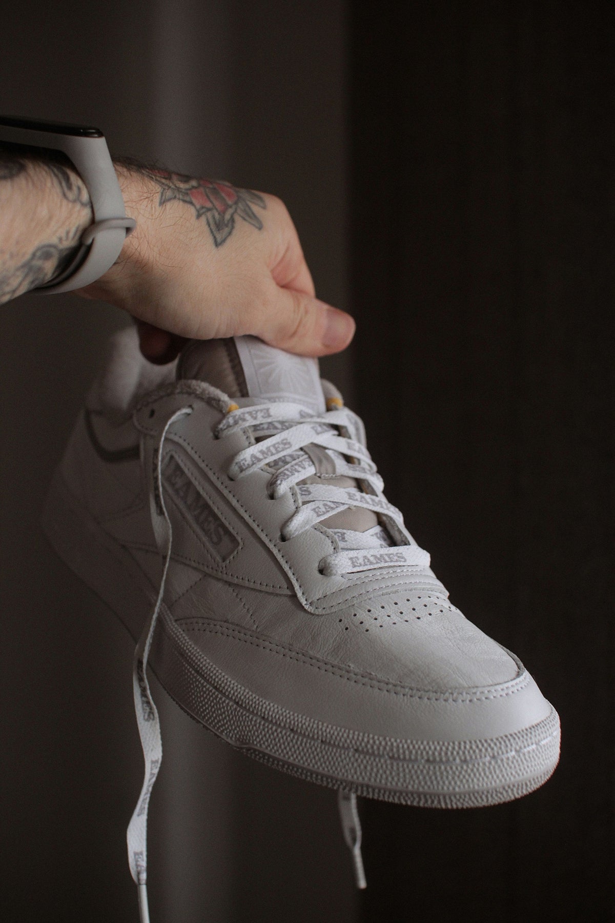 White Stitched Low Top — Photographic Demo — photograph 1. Photo: @felirbe; https://unsplash.com/photos/a-person-holding-a-pair-of-white-sneakers-7RhUBg1QROk. Photographic demo.