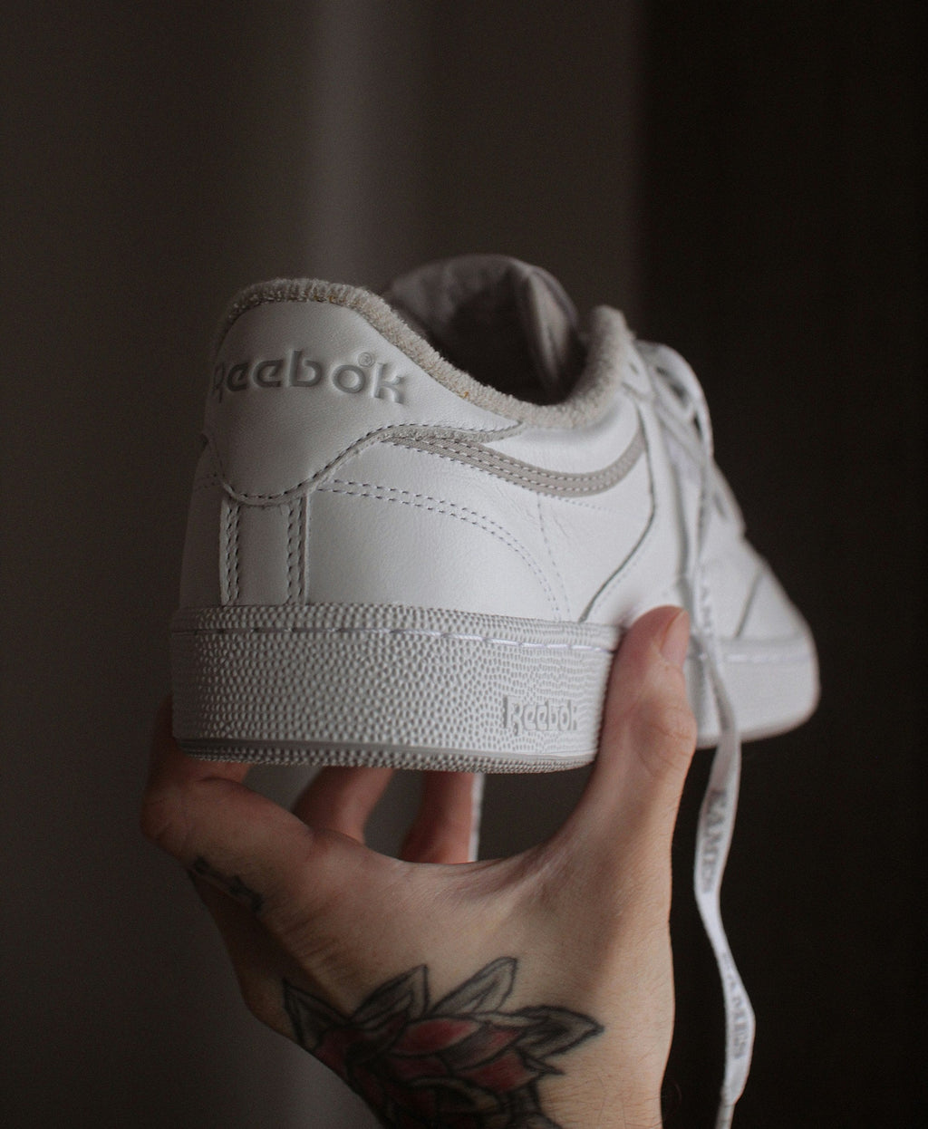 White Stitched Low Top — Photographic Demo — photograph 2. Photo: @felirbe; https://unsplash.com/photos/a-person-holding-a-white-shoe-in-their-hand-rp8F7ZHDqKE. Photographic demo.